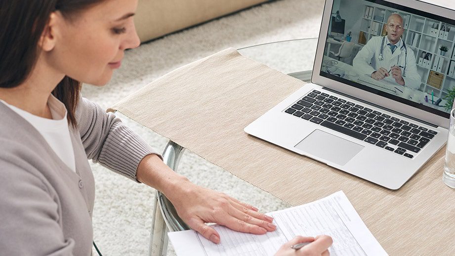 Young woman filling in health insurance form and watching online video