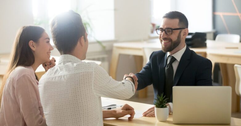 Smiling lawyer or financial advisor handshaking senior couple at