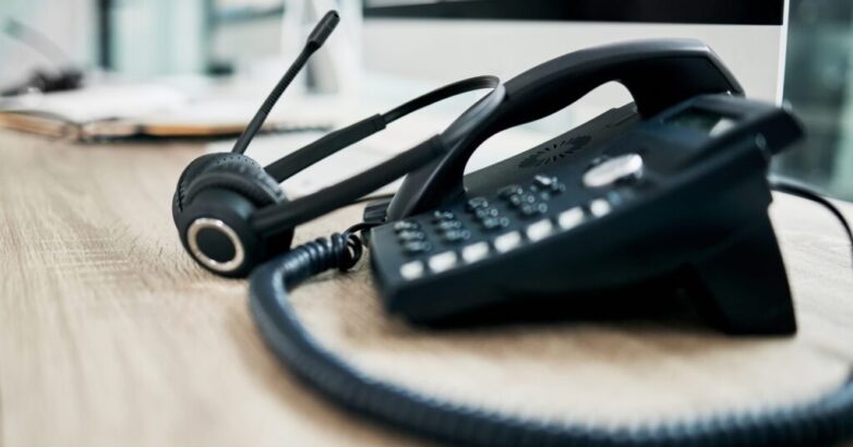Telephone, contact us with call center, communication and headphone with microphone on work desk. Contact center, customer support and phone, consulting and customer service with callcenter voip.